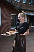Freundliche Kellnerin serviert Buchweizenpfannkuchen und Würstchen im Museums-Café Restaurant am Emsland Moormuseum, Groß Hesepe, nahe Twist, Emsland, Niedersachsen, Deutschland, Europa