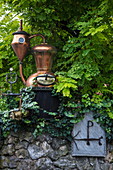 Old copper still on display at entrance to Edelbrennerei Haas distillery, Pretzfeld, Franconia, Bavaria, Germany