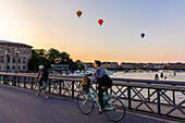 Radfahrerin auf der Skeppsholmsbron. Heißluftballons im Hintergrund , Stockholm, Schweden