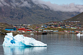 icebergs in front of the little town of colorful wooden houses, narsaq, greenland