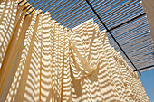 Washed bolts of cotton fabric hanging to dry on bamboo structure before being hand block printed, Bagru, Rajasthan, India, Asia