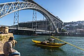 Dom Luis I Bridge between cities of Vila Nova de Gaia and Porto seen from Porto river bank, Portugal, View with so called Rabelo boat