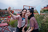 Smiling women taking selfie with smart phone on patio