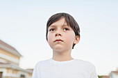Close-up of boy looking away while standing against clear sky