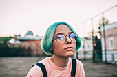 Portrait of teenage girl with green dyed hair wearing eyeglasses