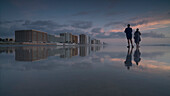 Young man and woman standing on shore at beach against sky during sunset, Daytona, Florida, USA