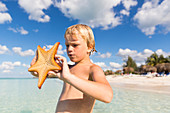 6 year old boy holding a starfish, dream beach at Cayo Levisa, swimming, beach holiday, tourists, lonely beach at Cayo Levisa, beautiful small sandy beach, turquoise blue sea, palm tree, family travel to Cuba, parental leave, holiday, time-out, adventure,