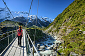 Frau überquert auf Hängebrücke Hooker River, Hooker Valley, Mount Cook, Mount Cook Nationalpark, UNESCO Welterbe Te Wahipounamu, Canterbury, Südinsel, Neuseeland