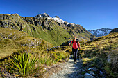 Woman hiking through mountain valley, Routeburn Track, Great Walks, Fiordland National Park, UNESCO Welterbe Te Wahipounamu, Queenstown-Lake District, Otago, South island, New Zealand