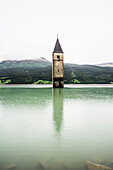 Steeple, bell tower of the submerged church of the village of Alt-Graun in Lake Reschen, or Reschensee Lake, Graun, Vinschgau, Curon Venosta, South Tyrol, Trentino-Alto Adige, Italy
