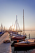 Menschen auf dem Steg am Sonnenuntergang am Ammersee, Bayern, Deutschland, Europa