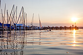 Menschen auf dem Steg am Sonnenuntergang am Ammersee, Bayern, Deutschland, Europa