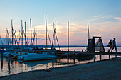 Paar am Steg beim Sonnenuntergang am Ammersee, Bayern, Deutschland, Europa