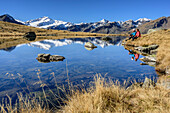 Mann und Frau sitzen an Bergsee mit Cevedale im Hintergrund, Martelltal, Ortlergruppe, Südtirol, Italien