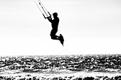 A silhouetted image of a kite surfer taking air over the Pacific Ocean in San Diego, California