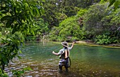 Tourists fly fishing with fishing guide in Lake Taupo area stream in New Zealand.