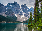 Moraine Lake and the rugged peaks of the Canadian Rocky Mountains with a boat in the water; Lake Louise, Alberta, Canada