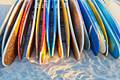 A stack of colourful longboard surfboards placed on the beach,; Waikiki, Oahu, Hawaii, United States of America