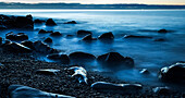 Beautiful blue misty ocean washing in against rocks on a West Coast beach; Greymouth, New Zealand