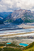 View of Kennicott Glacier and adjacent mountains in Wrangell-St. Elias National Park. Small colorful spots next to left-hand lake are tents; Alaska, United States of America