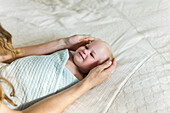 A mother's arms and hands cradle a swadled baby girl as she looks up to her mother; Sorrento, British Columbia, Canada