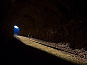 A man hikes through a tunnel in the Nevada spring desert; Boulder City, Nevada, United States of America