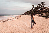 Woman walking along beach at Papaya Playa Resort in Tulum, Mexico