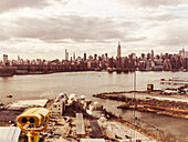 Coin-op Binoculars overlooking industrial district in Queens against skyline of New York, USA