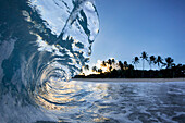 Wave breaking near shore of Ke Iki beach at sunset, north shore of Oahu, Hawaii Islands, USA