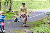 Father on skateboard accompanying sons on bicycles
