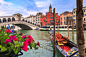 Flowers overlooking the Grand Canal with gondolas and the Rialto Bridge in the background, Venice, Veneto, Italy.