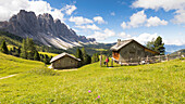 a view of the Kaserill Alm in Villnössertal with two old huts and the Geisler in the background, Bolzano province, South Tyrol, Trentino Alto Adige, Italy