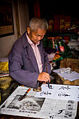 Man is writing with chinese idioms at Shigu Village or Stone Drum Village, Lijiang, Yunnan Province, China, Asia, Asian, East Asia, Far East
