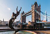 Juxtaposition of David Wynne's Girl With A Dolphin statue near Tower Bridge and Victorian engineering on the River Thames, London, England, United Kingdom, Europe
