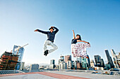 Couple dancing and jumping on urban rooftop