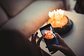 Mixed race girl photographing birthday cake with cell phone