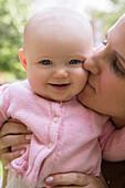 Portrait of Caucasian mother kissing cheek of baby daughter