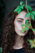 Porträt einer ernsten kaukasischen Frau hinter Blättern