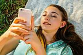 Caucasian girl laying on blanket texting on cell phone