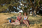 Laughing women relaxing on picnic blanket