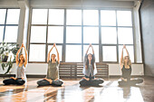Caucasian women stretching arms in yoga class