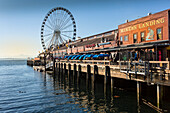 Seattle Great Wheel on Pier 57 in the foreground in late afternoon sunshine. Seattle, Washington State, United States of America, North America