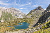 Turquoise lake between rocky peaks and meadows, Crap Alv Lejets, Albula Pass, Canton of Graubunden, Swiss Alps, Switzerland, Europe