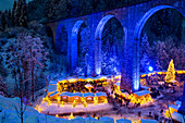 Verschneiter Weihnachtsmarkt unter einem Eisenbahn-Viadukt, illuminiert, Ravennaschlucht, Höllental bei Freiburg im Breisgau, Schwarzwald, Baden-Württemberg, Deutschland