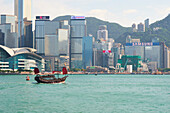 Traditional junk boat on Victoria Harbour with city skyline behind, Hong Kong, China, Asia
