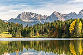 Lodge, forest and Karwendel Alps reflected in the waters of Gerold Lake, Krun, Upper Bavaria, Bavaria, Germany.