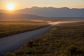 Car on dusty road at sunset, Grand Teton Park, Wyoming, United States of America, North America