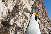 A man ice climbing up a frozen waterfall called Cascade Falls in a basin right above the historic downtown of Ouray, Colorado, USA