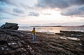 Woman standing on rocky shore, Isle of Skye, Scotland, UK