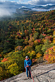 Front view of climber standing on front of colorful forest, North Conway, New Hampshire, USA